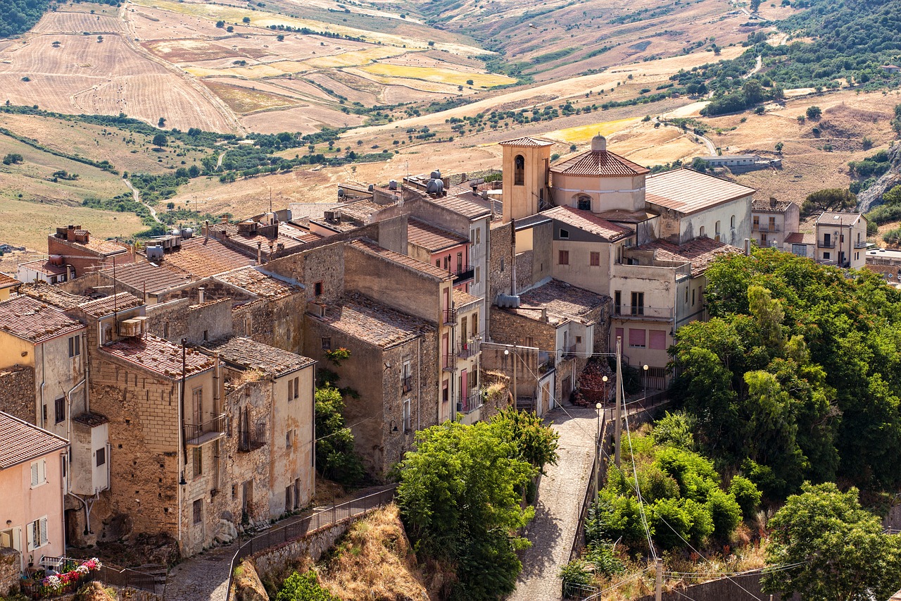 Borgo siciliano autentico con stradine acciottolate e case in pietra, immerso nella bellezza naturale.