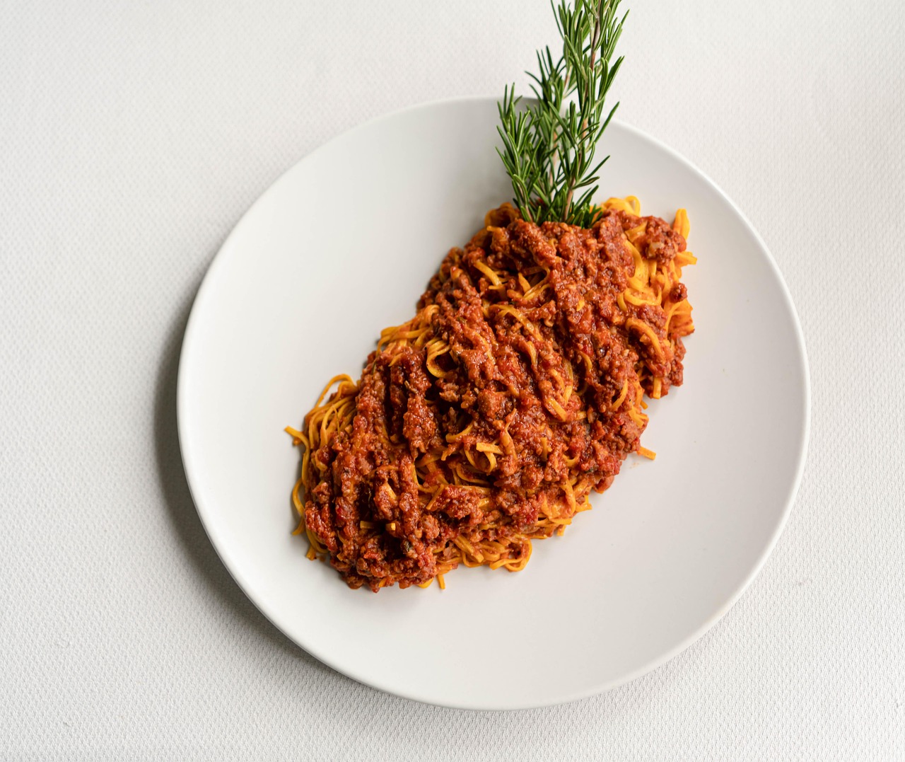 Ragù personalizzato in un piatto decorato, con ingredienti freschi e aromatici.