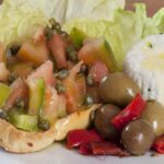 Caponata siciliana servita in un piatto, con melanzane, pomodori, olive e capperi.