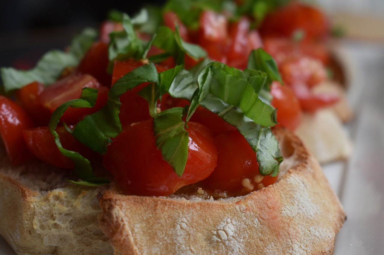 Bruschette al pomodoro con basilico, pronte da servire su un tagliere di legno.