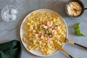 Pasta con crema di gamberi, piatto gourmet colorato e invitante, servito in un elegante piatto bianco.